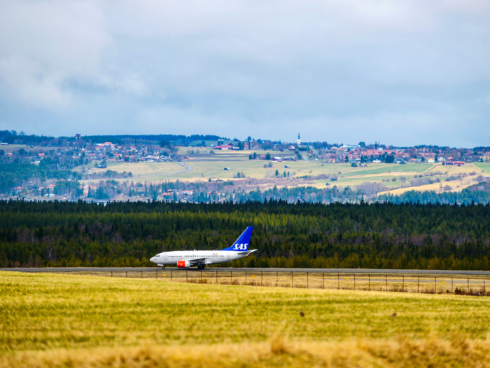 Bilde av et SAS fly som lander på en landlig flybane med frodige og grønne omgivelser i bakgrunnen.